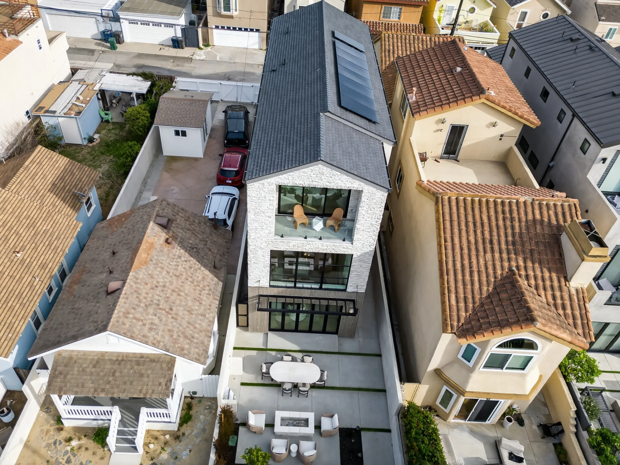 Daytime aerial drone photo of modern three-story luxury home with stone facade