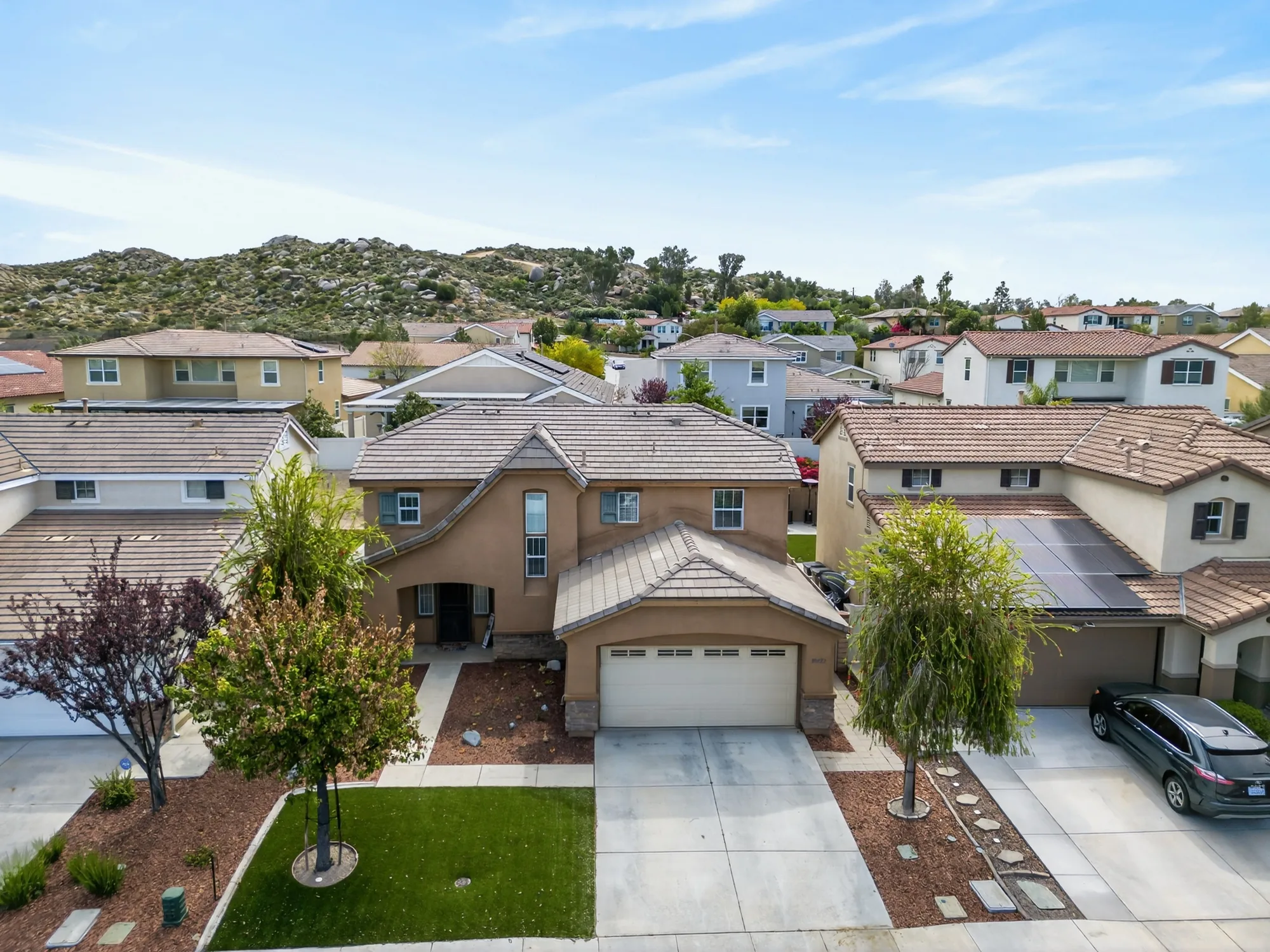 Aerial drone photo of Inland Empire two-story home with boulder mountain backdrop