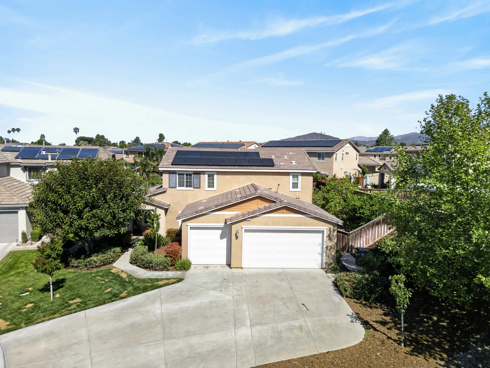 Daytime aerial exterior of two-story stucco home with solar panels