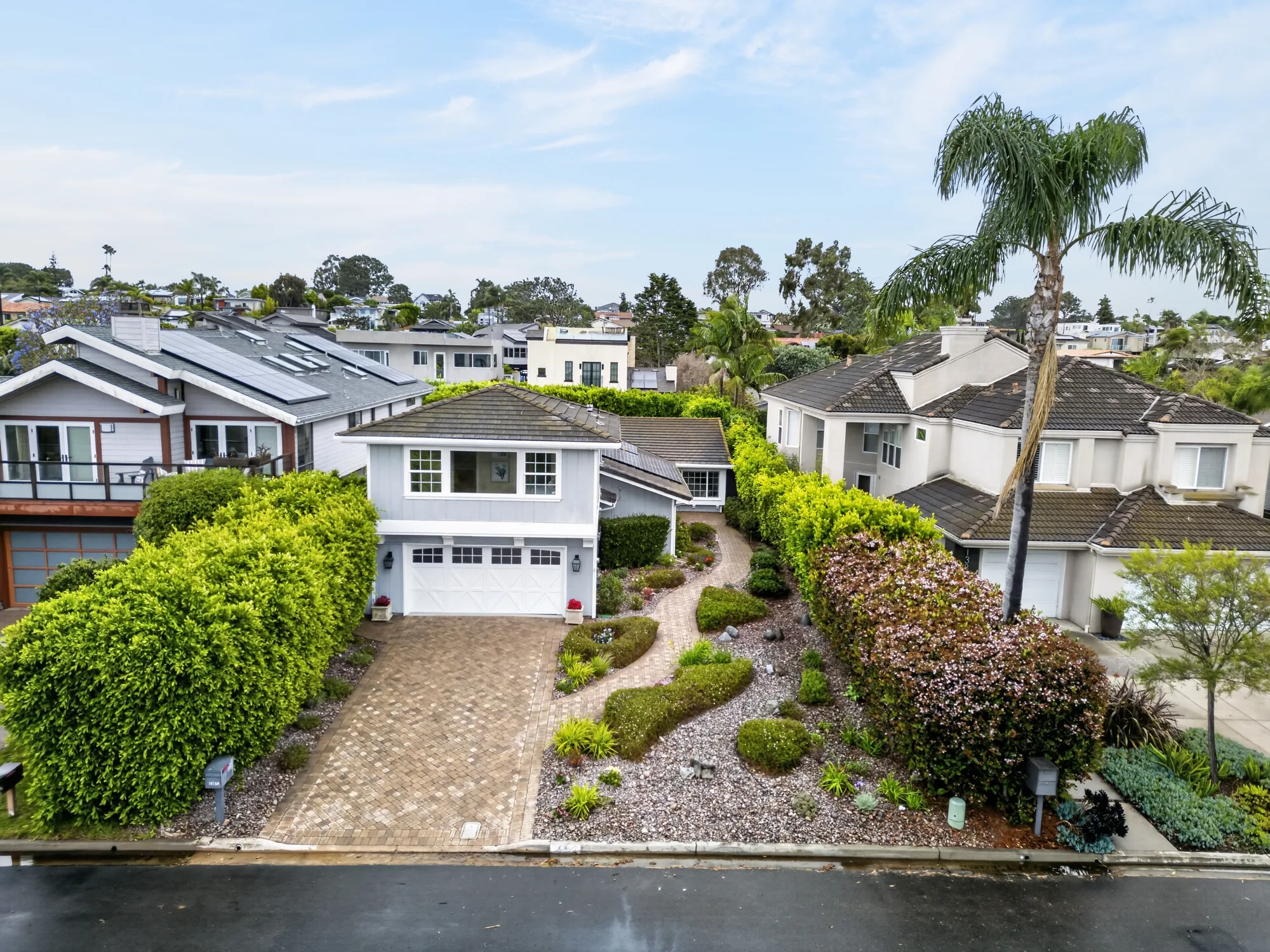 Daytime drone exterior of coastal-style two-story home with palm tree