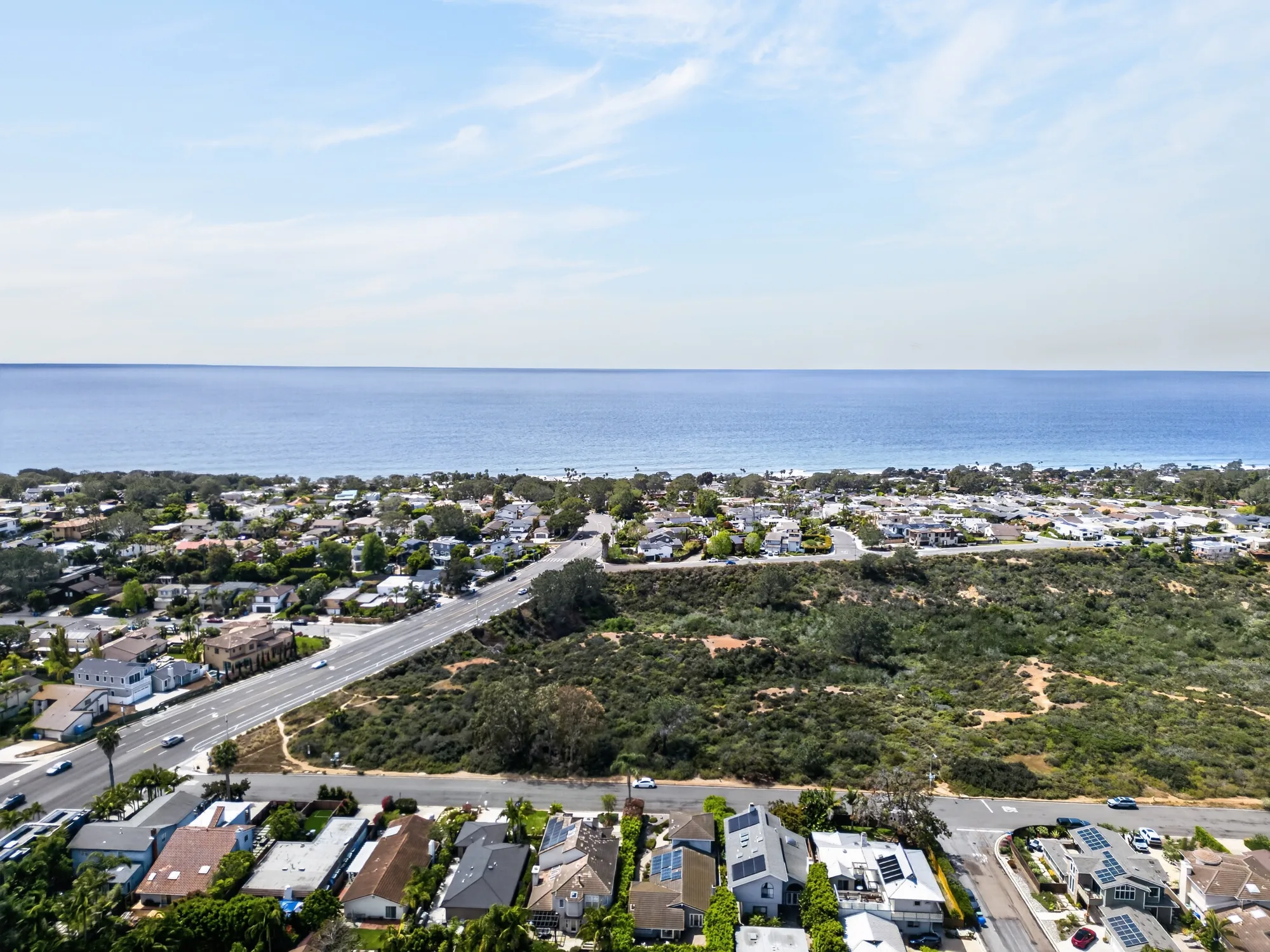 Wide aerial drone photo of coastal neighborhood with ocean visible on horizon