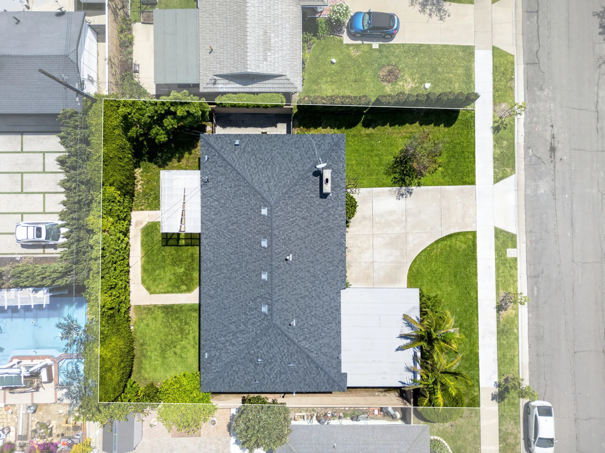 Overhead drone shot of single-story home with property lines and neighboring pool