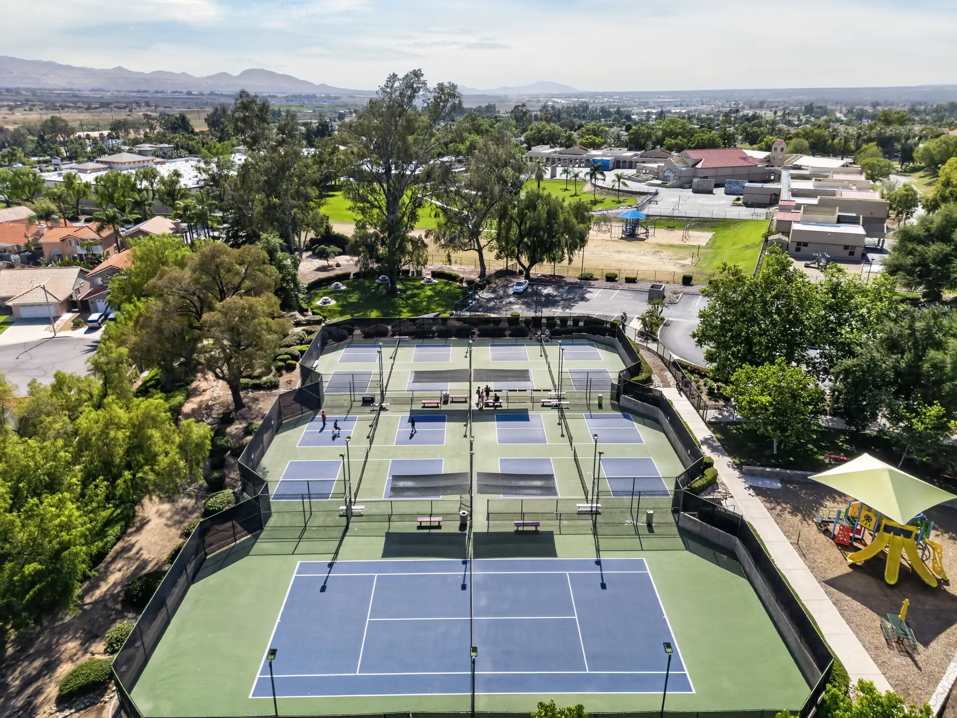 Aerial drone photo of community tennis and pickleball courts with playground