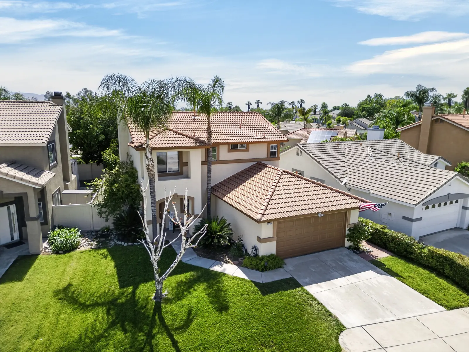 Drone aerial of same home showing roof, palm trees, and surrounding neighborhood