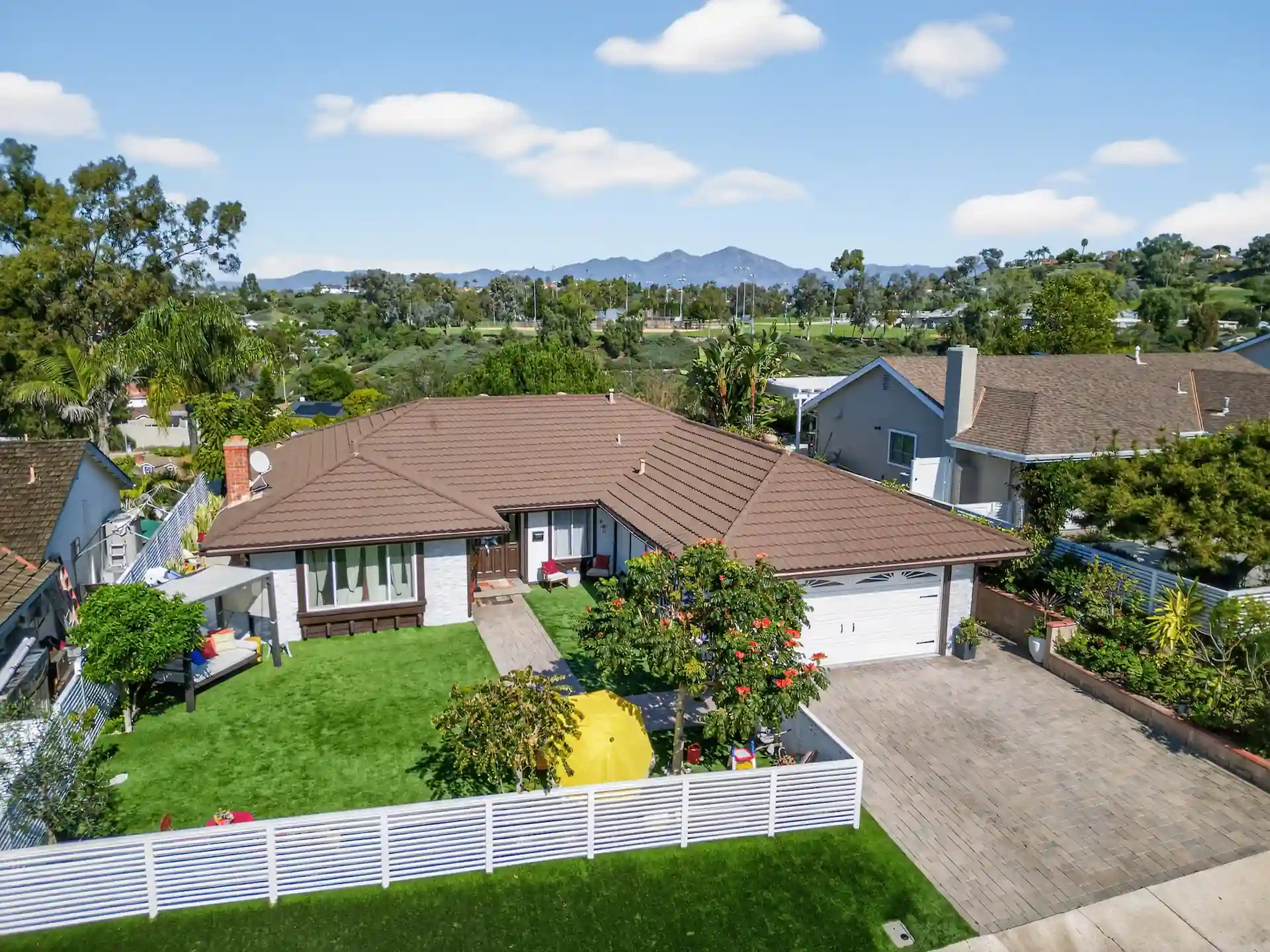 Low-angle drone photo of Orange County single-story home with mountain backdrop
